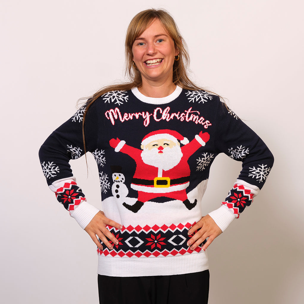 En smilende kvinde med hænderne i siden iført en julesweater.